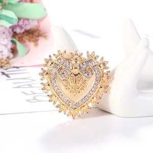 Baroque vintage gold heart brooch with sparkling rhinestones on an elegant hand prop