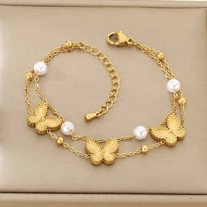 Detail of a gold double-layer butterfly chain bracelet with white pearls on a leather box