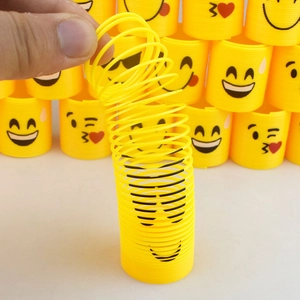 Detail of yellow rainbow spring toy being stretched by hand featuring emoji smile patterns