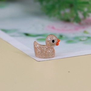 Close-up of a mini glow-in-the-dark resin duckling with gold glitter and orange beak