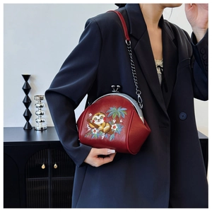 Detail of dark red shell bag featuring intricate sloth embroidery and silver metal clasp