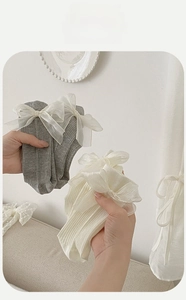 Close-up of lolita style crew socks featuring oversized lace bows and rib knit texture