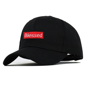 Detail of red Blessed embroidery on black cotton baseball cap showing fabric texture
