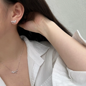 Detailed close-up of a silver butterfly jewelry set with sparkling zircon inlays on skin
