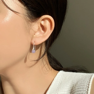 Detail of silver drop earring with lavender translucent bead on a model ear
