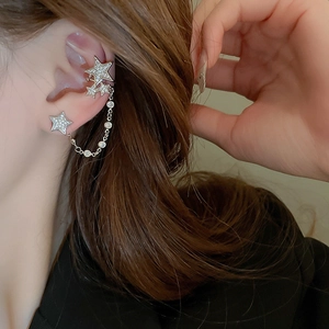 Silver star ear cuff with chain link and sparkling zircons worn on a model's ear