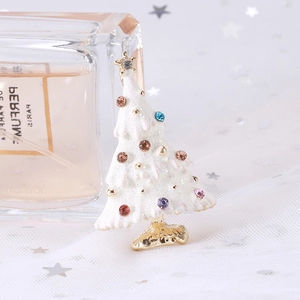 Close-up of a white enamel Christmas tree brooch with colorful rhinestones on tulle