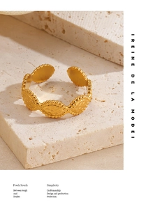 Detail of gold hammer-textured oval link ring with beaded edge on stone background