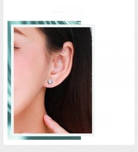Macro shot of silver bezel set round solitaire stud earrings on a model's ear