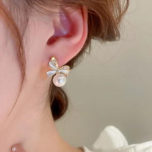 Macro shot of bow-knot pearl earring with gold-plated finish and zircon inlay on ear
