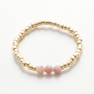 Detail of handmade gold beaded ring with three faceted pink natural stone accents