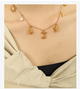 Detail of 18K gold-plated ocean-themed necklace with shell, starfish and J-letter charms