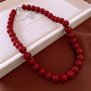 Detailed macro view of vibrant red glass beads of a necklace on a beige display tray
