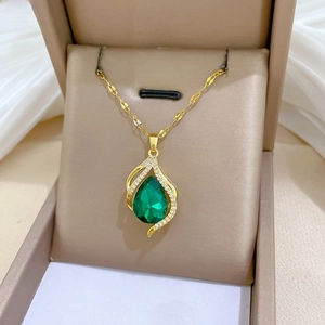 Macro detail of gold teardrop pendant with green stone and sparkling zircon accents