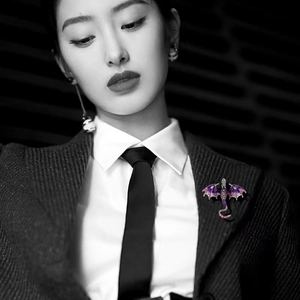 Close-up of purple enamel dragon brooch with inlaid crystals on a black suit lapel