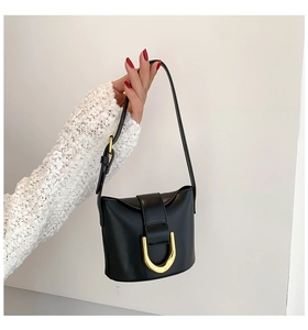 Detail of minimalist black leather shoulder bag with gold U-shaped metal buckle design