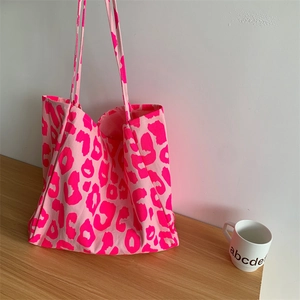 Detail of canvas tote bag showing pink leopard print texture and long shoulder handles