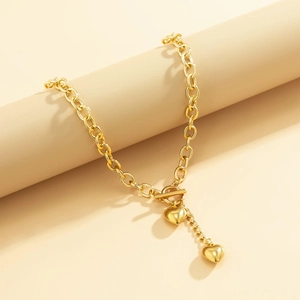 Detail of gold chunky chain necklace with toggle clasp and dual heart pendants
