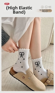 Macro detail of white ruffled crew socks with black bow embroidery and polka dot patterns