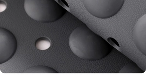 Detail of grey anti-slip bathroom mat texture featuring raised bumps and drainage holes