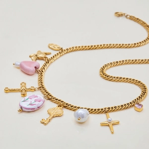 Detail view of 18K gold plated necklace with pink heart, cross, and pearl charms
