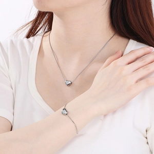 Vue détaillée de l'ensemble collier et bracelet cœur argenté porté par un mannequin mode