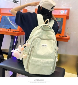 Détail du sac à dos en tissu gaufré vert menthe avec son pendentif lapin en peluche blanc