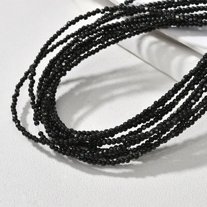 Macro detail of 2mm polished black shell beads arranged in multi-layer strands