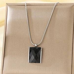 Close-up of a faceted black square pendant on a silver snake chain jewelry box