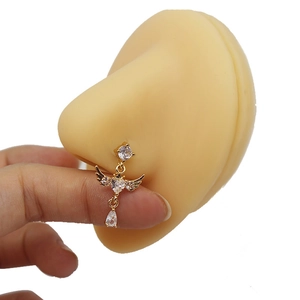 Macro view of gold nose stud with angel wings heart and zircon teardrop on silicone model