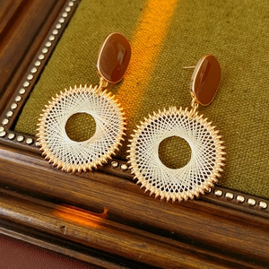 Macro detail of gold mesh round earrings with brown accents on green velvet background