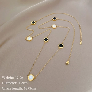 Detail of long gold necklace with black enamel and white shell Roman numeral pendants