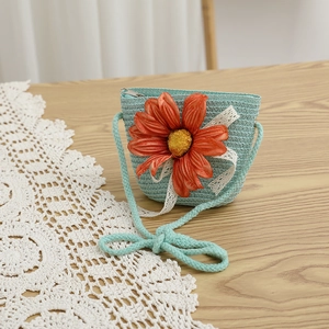 Détail d'un sac en paille bleue pour enfant avec fleur orange et bordure dentelle