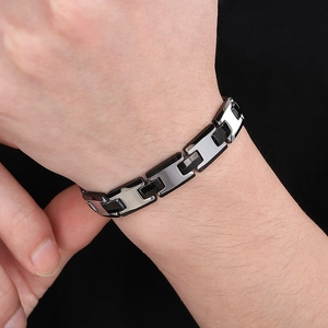 Detail of a minimalist black and silver H-link tungsten steel bracelet on a male wrist