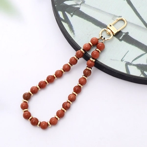 Detail of red gold sandstone beads with gold metal spacers and lobster clasp phone charm