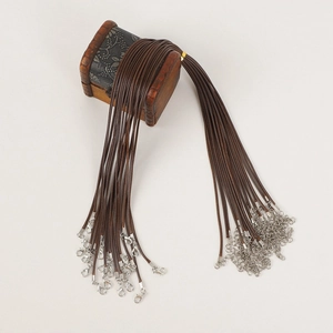 Close-up of brown braided necklace cords with metal lobster clasps on a wooden box
