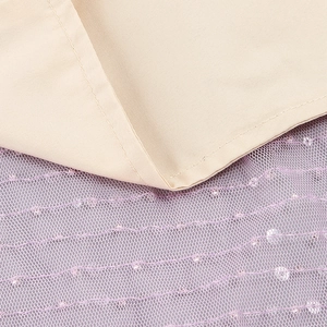 Gros plan sur le tissu champagne cousu avec des détails en maille à paillettes lilas
