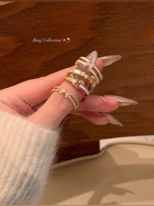 Close-up of stacked gold bow rings with pearl and enamel details on model hand