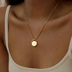 Golden stainless steel oval necklace featuring letter A pendant worn by a model