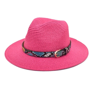 Close-up of pink straw fedora hat with snake print band and golden metal buckle