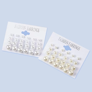 Set of 12 pairs of white pearl stud earrings in various sizes on a light blue background