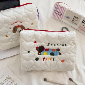 Detailed view of heart quilted fabric texture and puppy embroidery on white makeup bags