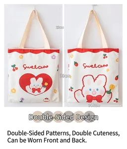 Detail view of white canvas tote bag with red scalloped edges and cute rabbit patterns