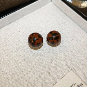 Macro view of polished round tortoiseshell resin earrings with vintage leopard pattern