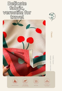 Close-up of soft cashmere-like scarf fabric with red cherry print and striped edges