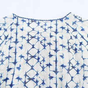 Vista dettagliata del colletto in maglia blu e del tessuto geometrico con fili argentati