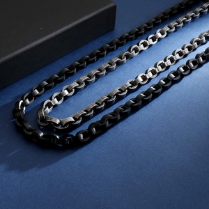 Detail of hiphop stainless steel chain necklaces in black and silver on a dark background