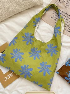 Green canvas tote bag with blue floral patterns on a white minimalist background