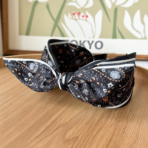 Detail of floral satin knot headband with striped edges on a wooden tray decor