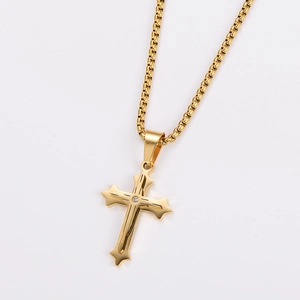 Detail of a gold-plated textured cross pendant with a center crystal on a box chain